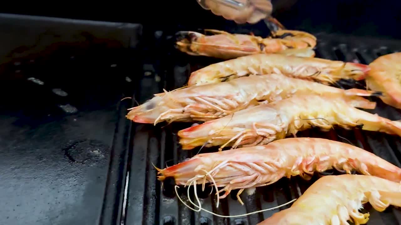 Prawns being grilled with tongs on barbecue