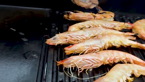 camarones siendo asados con pinzas en la barbacoa