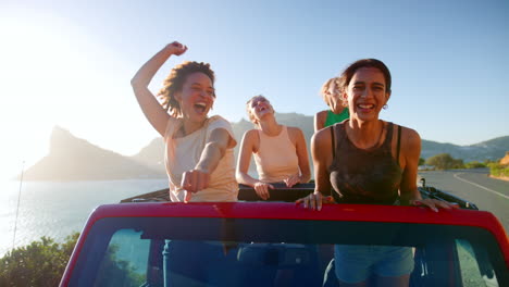 Amigas-De-Pie-A-Través-Del-Techo-Solar-Del-Coche-Bailando-En-Un-Viaje-Por-Carretera