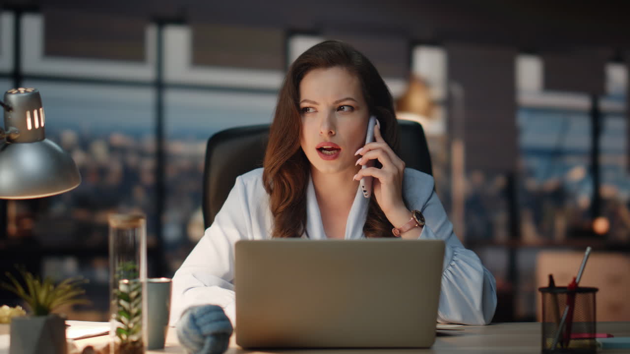 Confident boss calling mobile phone at evening city view office. Woman ...