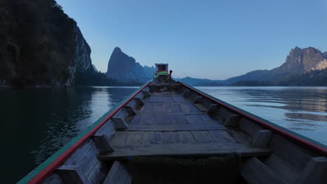 Clip-De-Timelapse-Que-Muestra-El-Frente-De-Un-Barco-De-Madera-Moviéndose-Sobre-Un-Lago-Tranquilo-En-El-Parque-Nacional-Tailandés,-Con-Empinadas-Montañas-Rocosas-Y-Selva-Tropical-Nativa