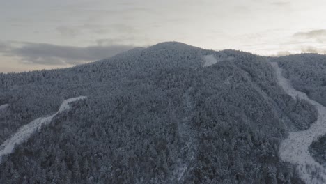 Flying-towards-the-snow-dusted-peak-of-an-abandoned-ski-mountain-at-sunset-AERIAL