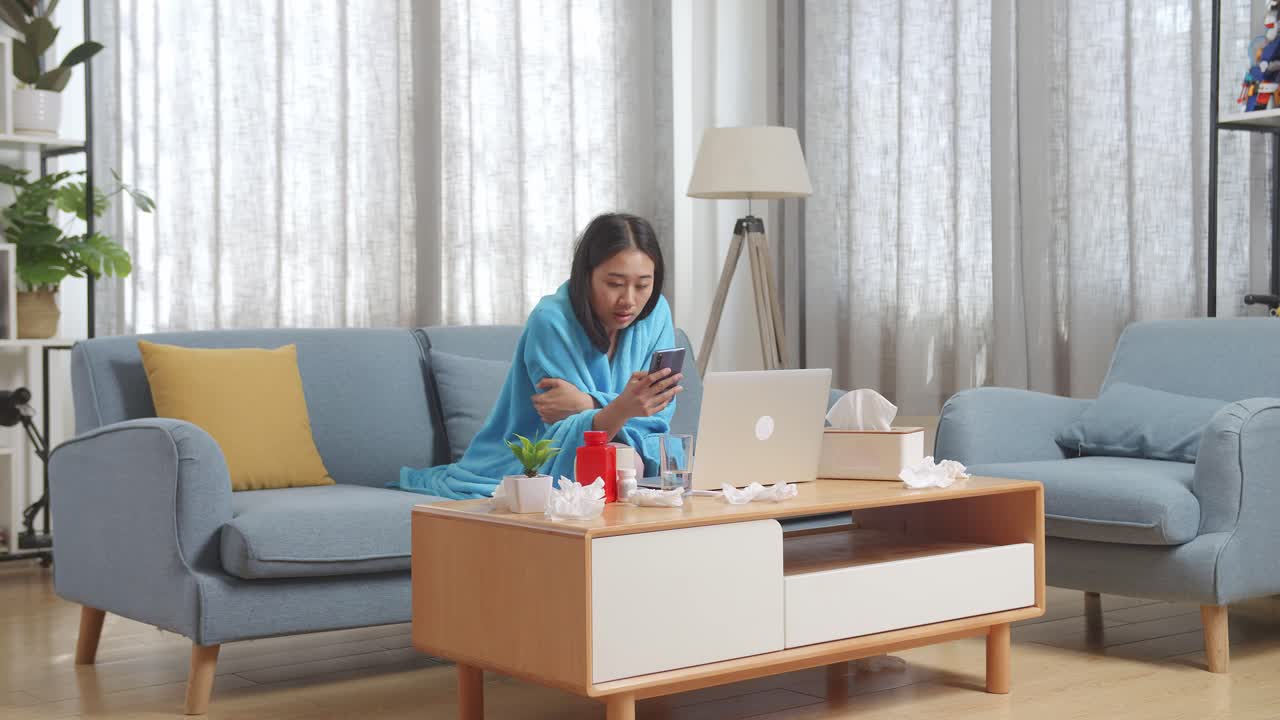 아픈 동안 집에서 휴식을 취하고 전화를 사용하는 여성