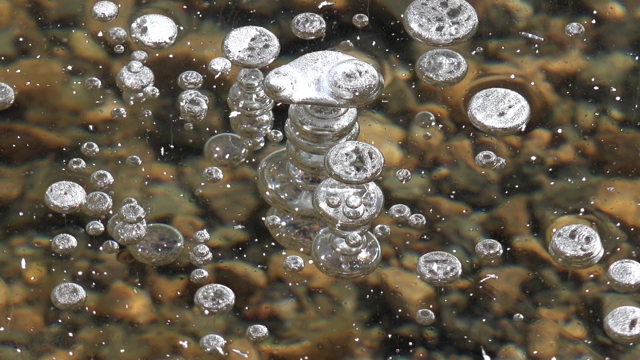 Bolle d'aria intrappolate sotto la superficie di un lago ghiacciato.