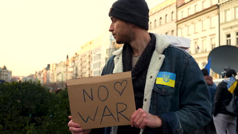 man with antiward protest sign and ukraine flag at a rally in prague