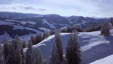 Beautiful-panorama-of-two-people-trekking-across-a-snow-covered-ridge-Hundwiler-Hoehe,-aerial-reveal