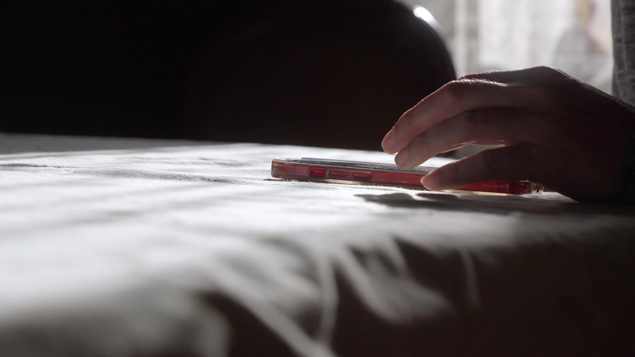 Et roligt, æstetisk nærbillede af en person, der sms'er på en smartphone, der ligger fladt på et bord, mens blødt morgensollys strømmer ind over. Ideel til projekter om ren livsstil, kommunikation og moderne fortællinger.
