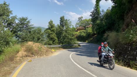 lalitpur, nepal - october 12, 2021: motorcycles driving on a paved road in the mountains with the himalayan mountains in the background