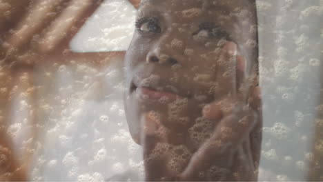 animation of sea lapping on beach over happy african american woman moisturising face