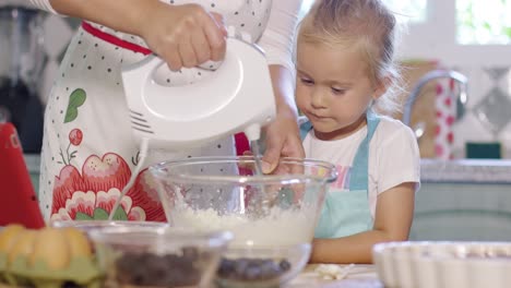 Little-girl-watching-her-mother-whisk-cream