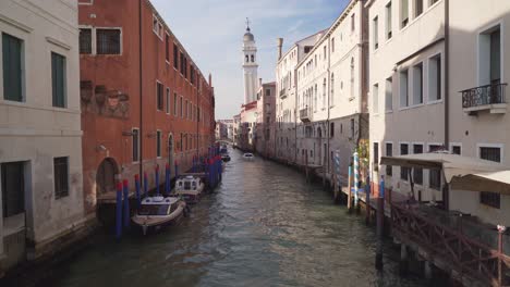 Kleiner-Kanal-In-Venedig,-Italien,-An-Sonnigen-Tagen-Mit-Turmglocke-Als-Hintergrund