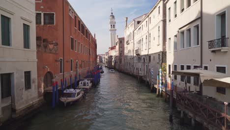 small canal in venezia italy during sunny day with towerbell as background