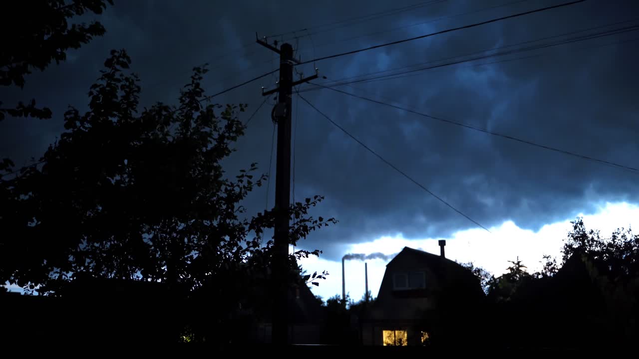 Thunderstorm in the countryside. Lightning on the dark sky in the evening. Dark storm filled sky over the rural houses in summer.