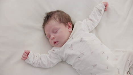 cute, sleeping and newborn baby on a bed at a home