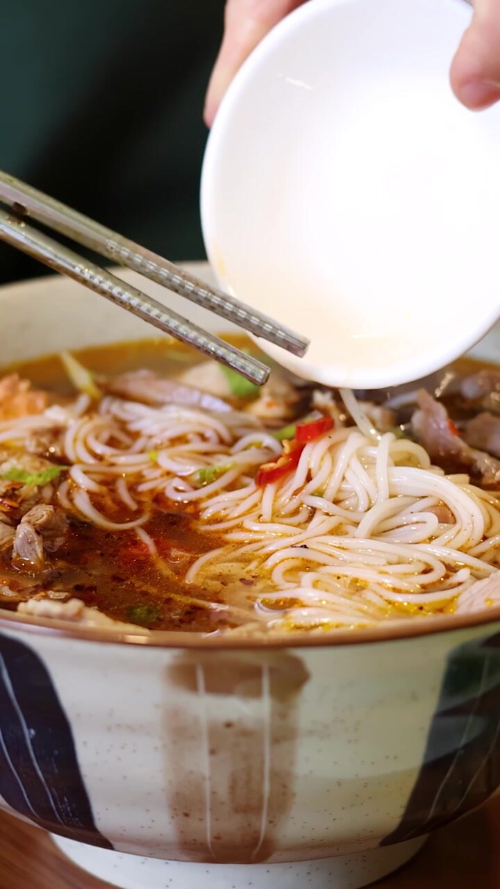 Aggiungere peperoncino fresco a una ciotola di zuppa di noodle di manzo vietnamita