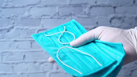 hand holding a teal medical mask