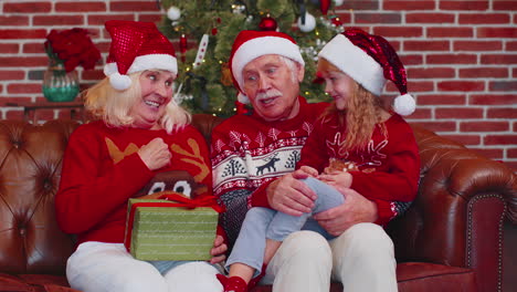 abuelos mayores felices con la nieta disfrutando de una agradable conversación en la habitación de la casa de navidad