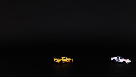 two toy cars moving across a dark background