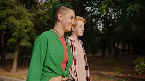 two girls with short hair and bright hair color in plaid shirts walk, communicate with each other and flirt during their date in the park