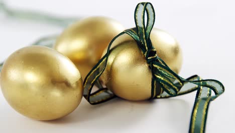 golden easter eggs tied with ribbon on white background