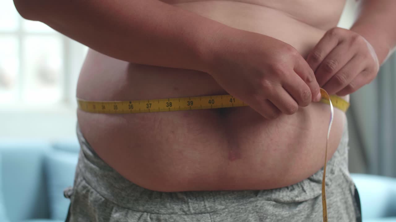 primer plano de un hombre gordo midiendo su vientre