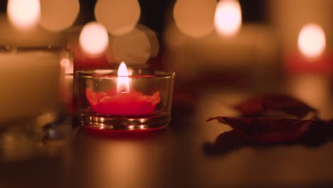 close up of romantic lit red and white candles burning on black background with bokeh lighting 5