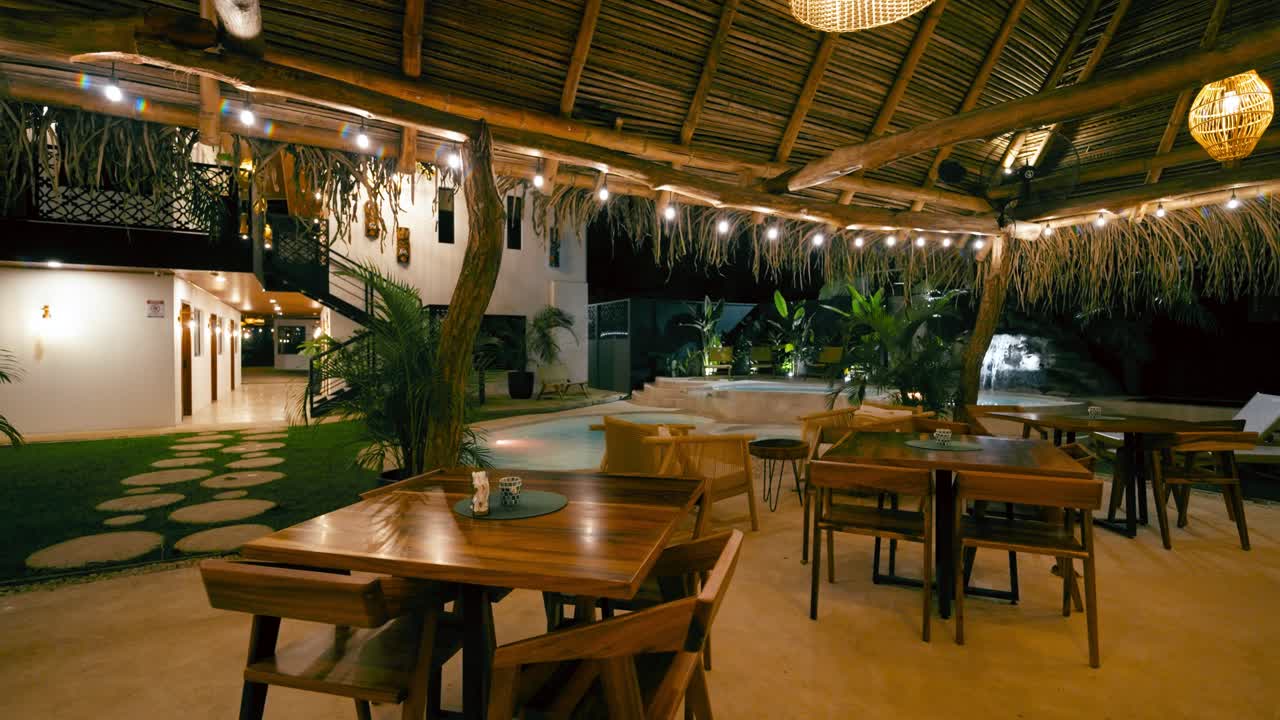 Illuminated Tropical Resort Dining Area with Pool at Night