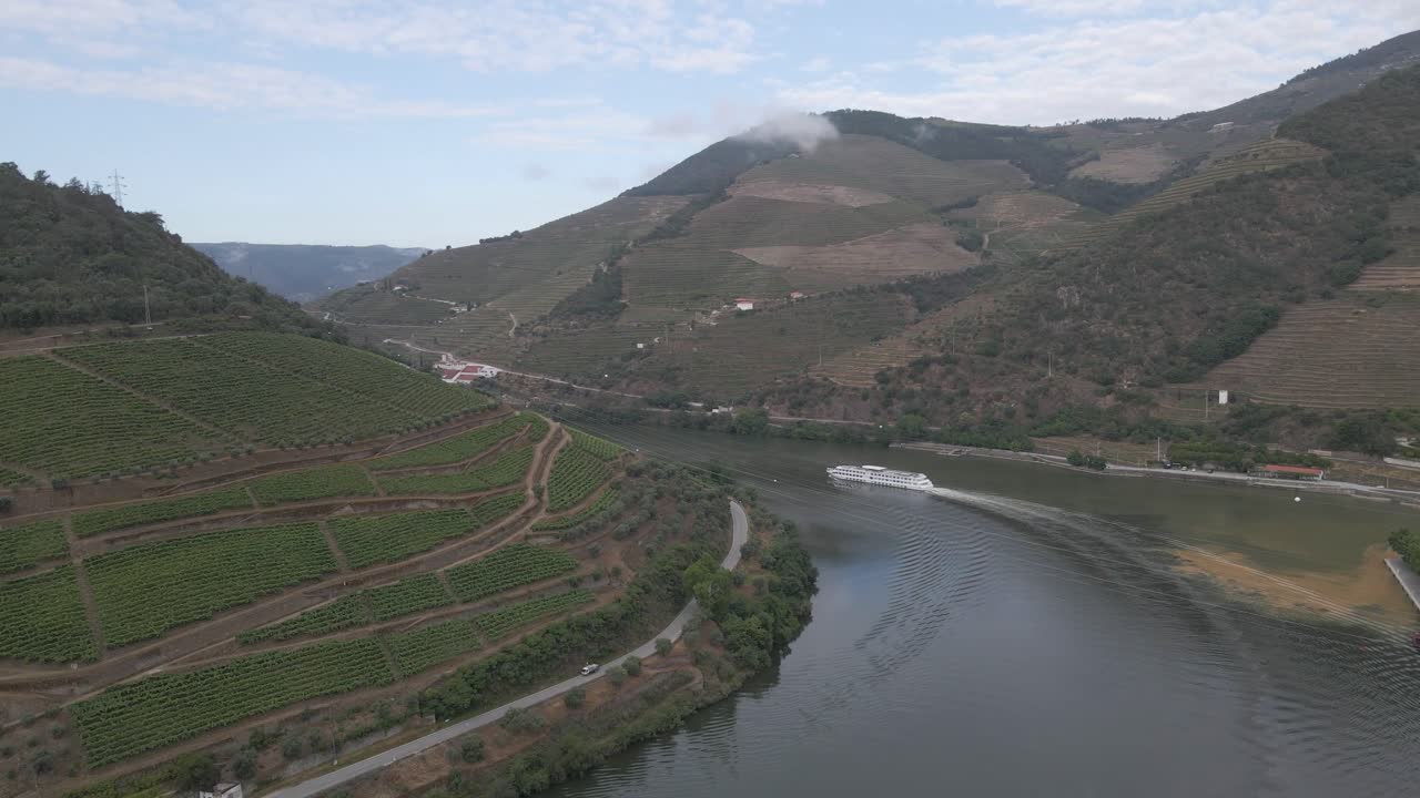 Vista aerea della città vinicola di Pinhão, Portogallo. Drone che si muove verso destra sopra il fiume Douro, mostrando i vigneti e una nave turistica che naviga lungo il fiume