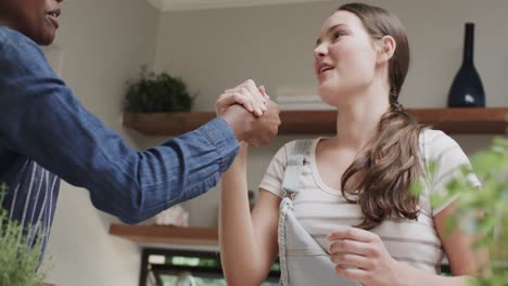 Two-happy-diverse-teenage-female-friends-cooking-and-high-fiving-in-slow-motion