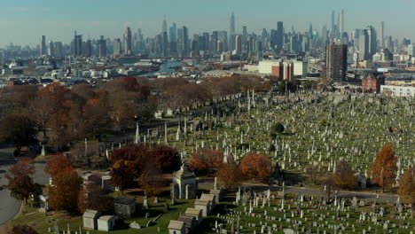 Aerial-view-of-historic-tombstones-on-Calvary-Cemetery.-Tilt-up-reveal-of-skyline-with-Manhattan-skyscrapers.-Queens,-New-York-City,-USA