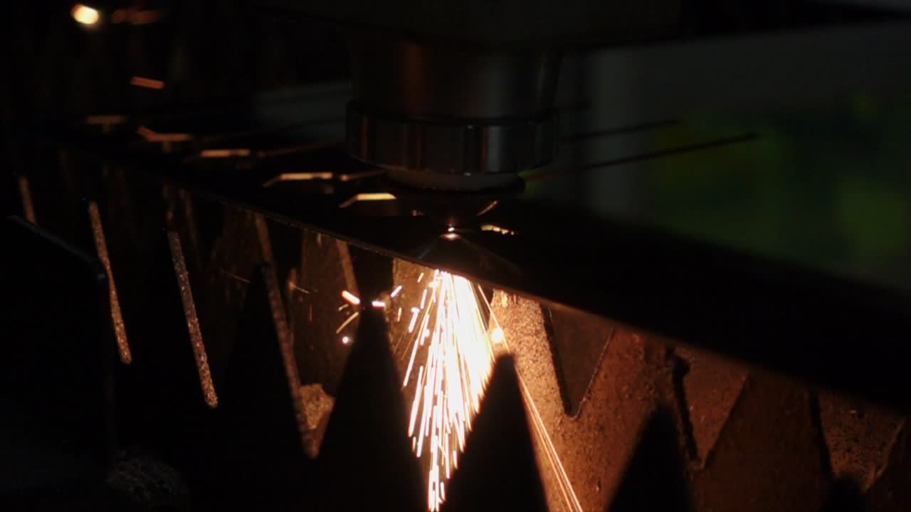 Potente macchina CNC laser al plasma che crea scintille da una lastra di metallo, scuro