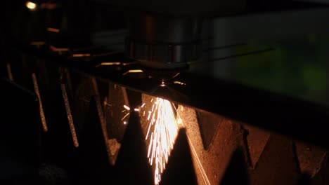powerful plasma laser cnc machine creating sparks from sheet of metal, dark