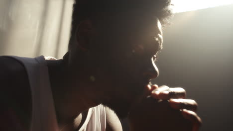 regretful black inmate sitting in deep thought in prison cell