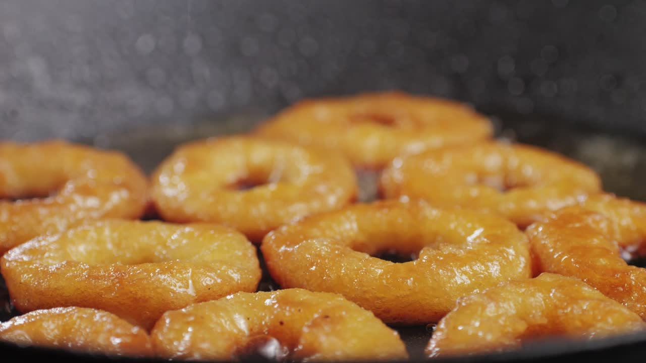 Fried crispy onion rings in a frying pan with oil close-up macro. Roasted onion rings for snacks at bar, cafe. Fast food. Delivery. Beer snacks