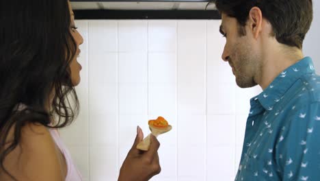 mujer alimentando a un hombre mientras cocina en la cocina