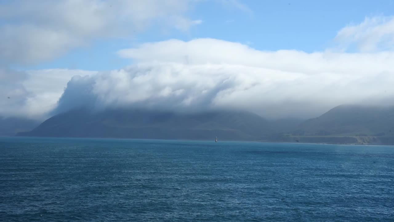 긴  구름이 뉴질랜드 북섬 해안의 절벽 위에 매달려 있습니다.