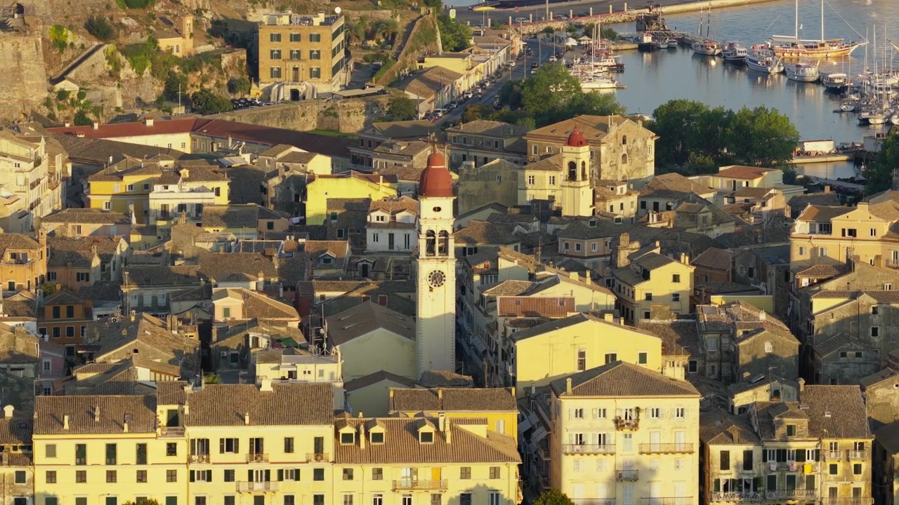 Scorcio della città vecchia di Corfù all'ora d'oro con il campanile della Chiesa di San Spiridione e le case addossate a ridosso della costa.