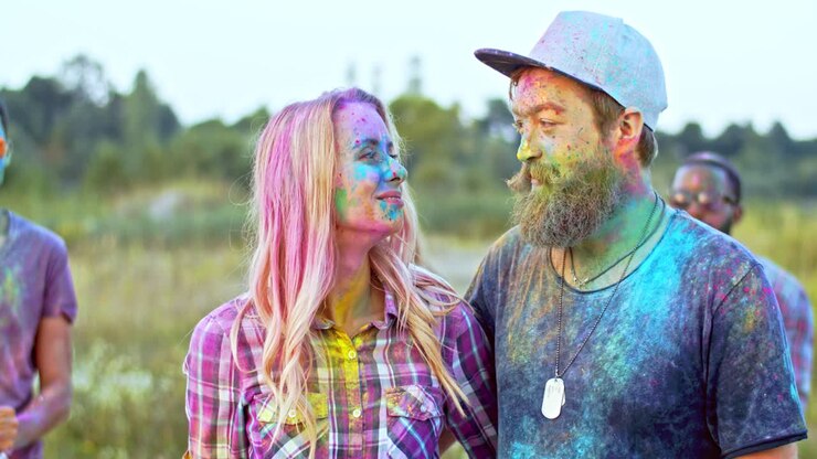 Close Up Of The Jhappy Couple In Colorful Paints At The Holi Fest Celebration Hufing And Smiling To The Camera