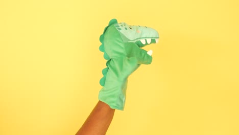 green dinosaur hand puppet on yellow background