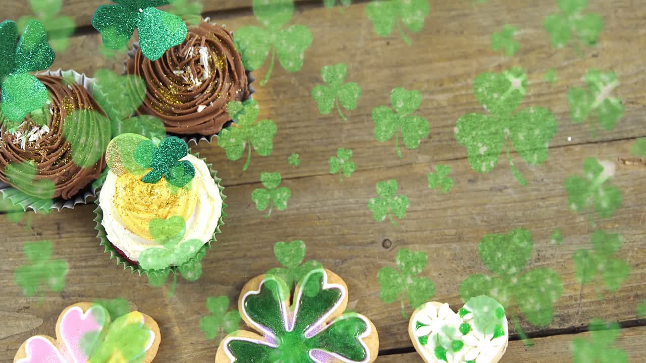 Animation of st patrick's day shamrock and cupcakes on wooden background
