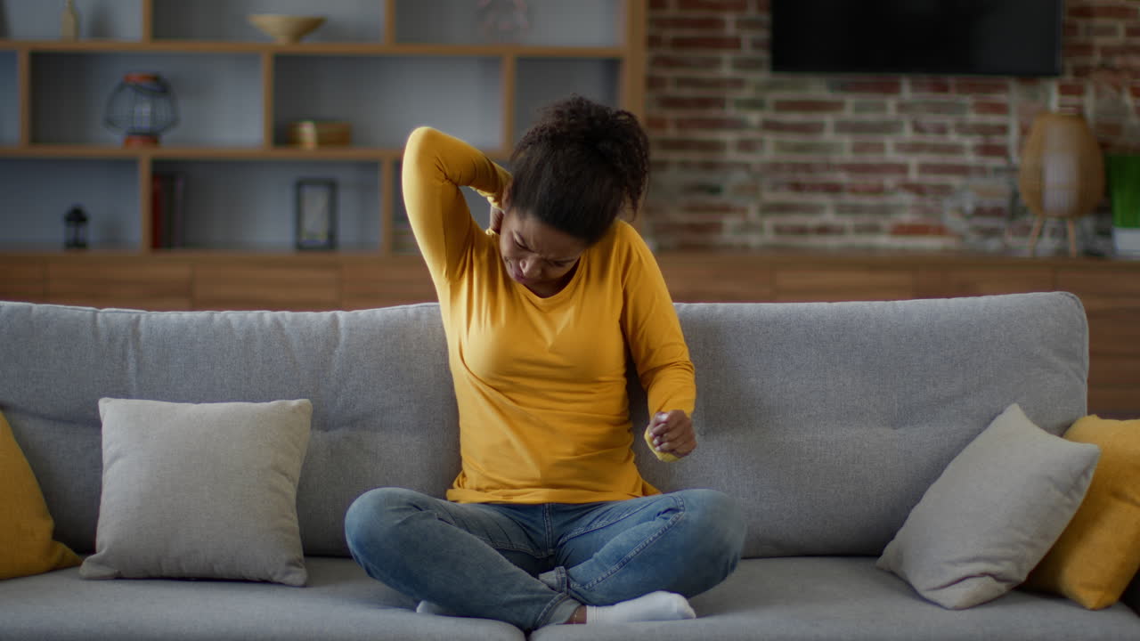 Woman experiencing neck pain on couch