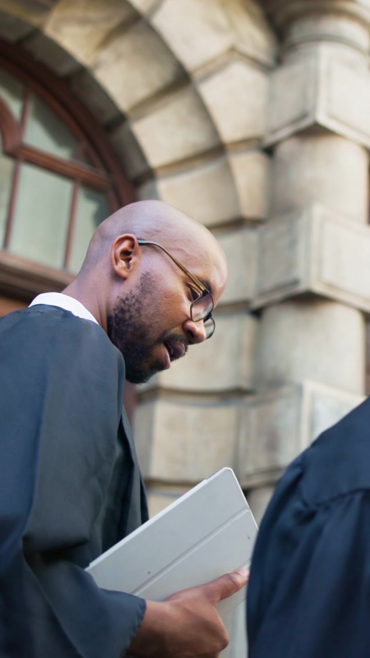 Lawyer in Academic Robe Holding Tablet Outside Courthouse