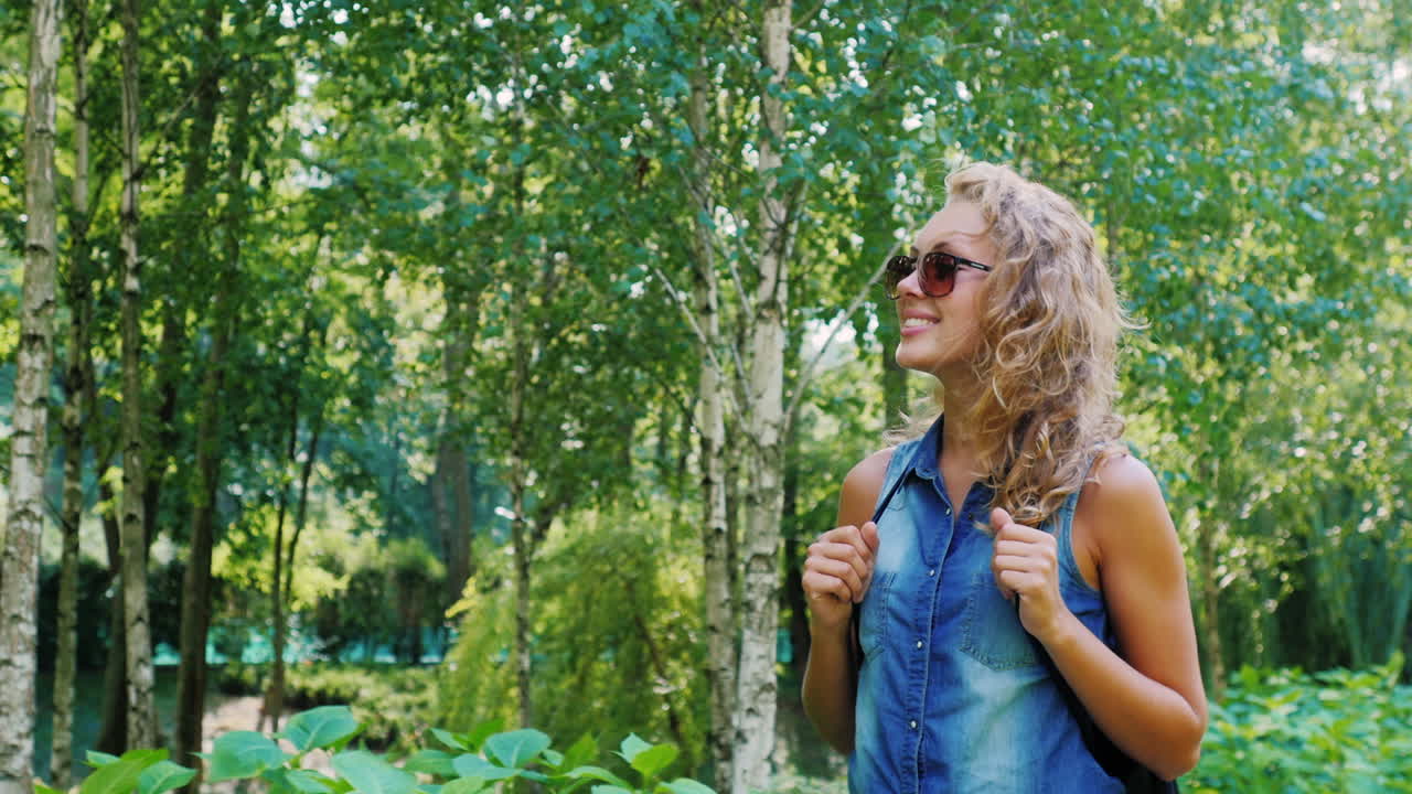 한 젊은 매력적인 여성이 여름날 단정한 공원을 산책한다