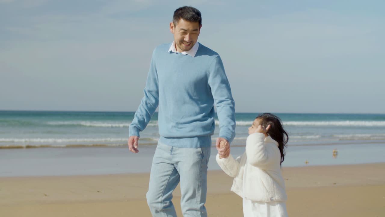 japanese father and his cute little daughter walking along seashore, then  man hugging his child