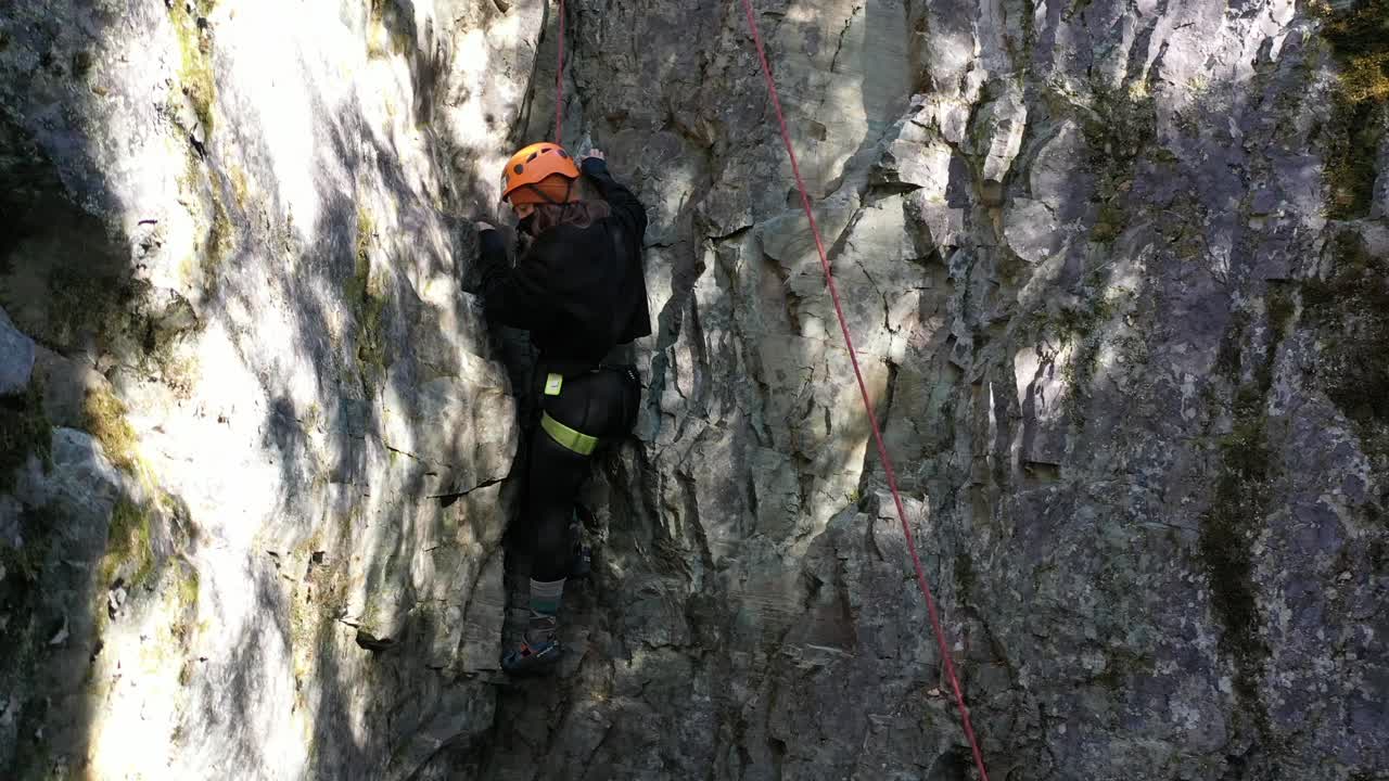Amateur Climber In Safety Gear Struggling To Climb On The Rock Wall In Whitefish, Montana. static