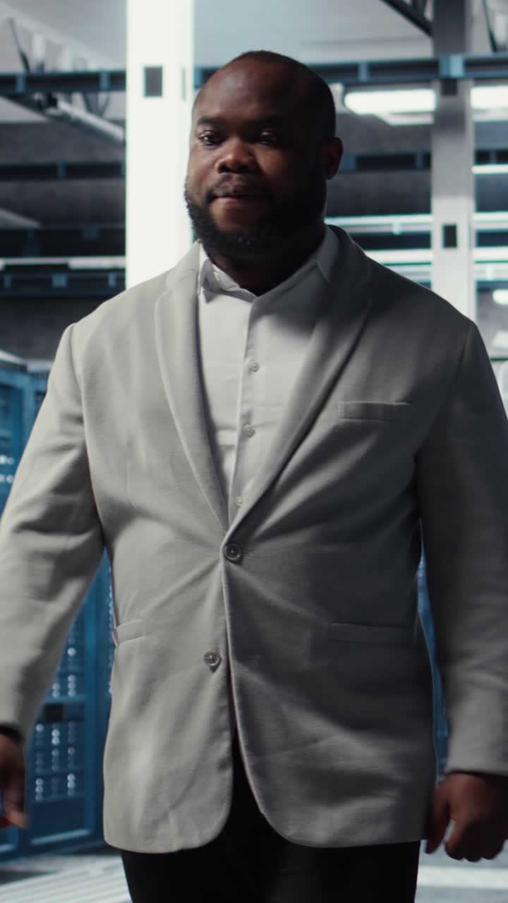 Vertical video Smiling engineer in server hub monitoring data center energy consumption