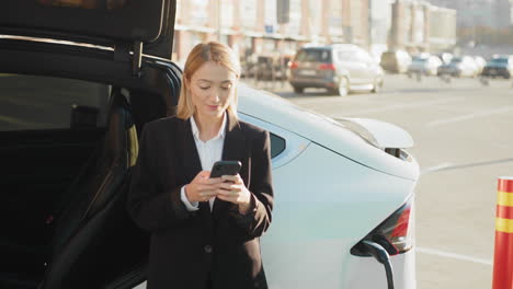 mujer de negocios cargando un coche eléctrico