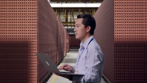 worker using a laptop in a brick factory