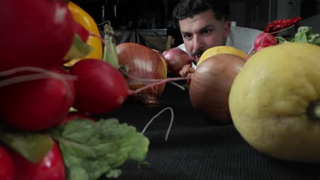 Chef-picks-onions-in-a-still-life-with-radishes,-peppers,-lemons-and-lettuce