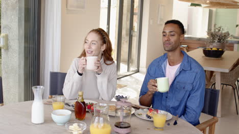 diverse couple enjoying breakfast together at home, sharing joyful moment